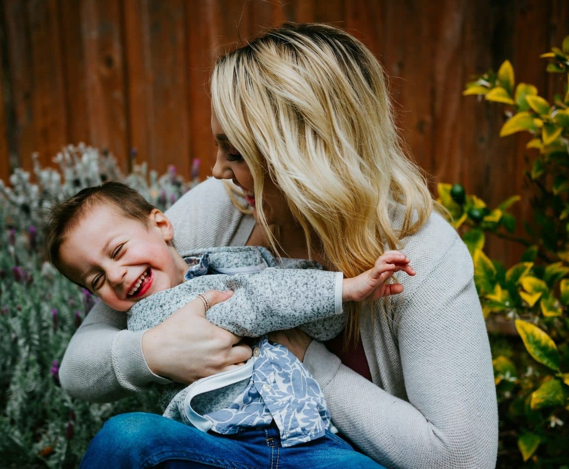 Mother laughing with her young daughter outdoors